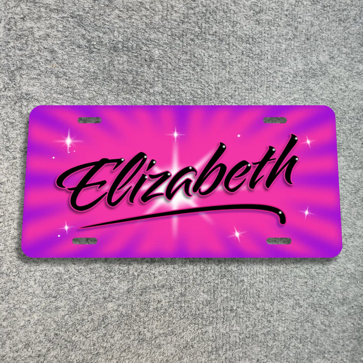 A license plate with a vibrant pink and purple sunburst design, featuring the name 'Elizabeth' in black cursive script with a white glow and star accents, displayed on a gray textured background.