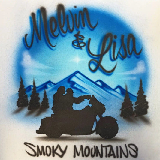 Custom airbrushed design featuring a blue mountain landscape with pine trees, a black silhouette of a couple on a motorcycle, and the text 'Melvin & Lisa' and 'Smoky Mountains'.