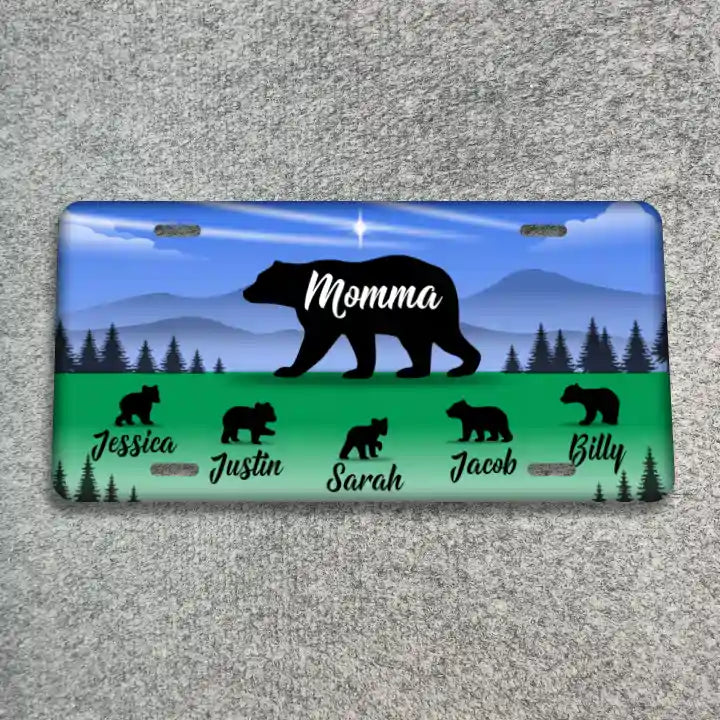 A license plate featuring a blue sky and mountain background with a large black bear silhouette and the word 'Momma' in white. The bottom section is green with smaller black bear silhouettes and the names Jessica, Justin, Sarah, Jacob, and Billy in white script.
