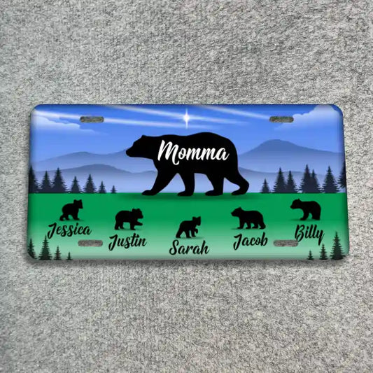 A license plate featuring a blue sky and mountain background with a large black bear silhouette and the word 'Momma' in white. The bottom section is green with smaller black bear silhouettes and the names Jessica, Justin, Sarah, Jacob, and Billy in white script.